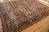 Vintage Mahal carpet corner: chestnut, navy, gold samovar border, floral field, softened pile.