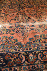 Antique Lilihan carpet's detailed floral spray, dusty rose field, and navy blue border with wear.