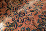 Worn dusty rose ground with navy blue floral spray pattern on antique Lilihan carpet.