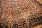 Antique Lilihan carpet corner with dusty rose floral field, navy blue border, visible foundation wear.