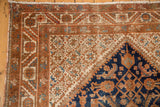 Corner of vintage Hamadan rug: navy spandrel, sand Herati motif field, madder borders.