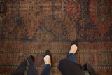 Visible foundation and muted tones across the geometric floral design of this antique Belouch carpet.