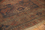 Antique Belouch rug pile with faded red, navy geometric patterns, even wear, and fringe.