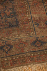 Detail of antique Belouch carpet: geometric patterns, worn texture, visible foundation, and fringe.