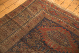 Geometric patterns, visible wear, and navy, dark red, brown tones on an antique Persian Belouch carpet.
