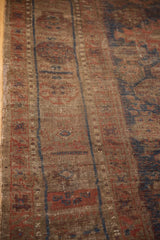 Worn pile of antique Belouch carpet, showing exposed knot heads and navy, red geometric patterns.