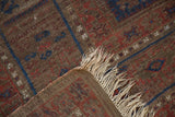 Antique Belouch carpet fringe with worn pile, revealing geometric navy and red motifs.