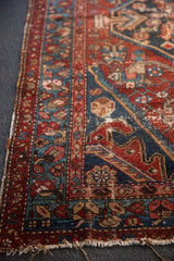 Antique Hamadan rug side view, geometric border in wine red, navy, with visible wear.