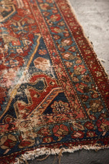 Antique Hamadan rug corner, showing tattered fringe, exposed foundation, and geometric motifs.