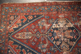 Detail of antique Hamadan rug showing wear, dark red, navy, and ivory geometric pattern.