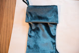 Folded cuff and hanger loop of a silvery teal velvet stocking.