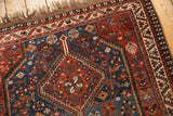 Detail of vintage Afshar rug: sapphire blue field, rust red geometric motifs, and animals.