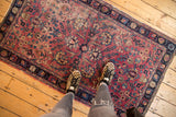 Antique Persian Kerman rug corner with low pile, cochineal red vinery, navy border.
