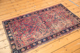 Antique Kerman rug's cochineal red field with delicate floral vinery, showing visible wear.