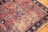 Hard wear and tatter on antique Kerman rug's cochineal red floral field.