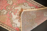 Hand-knotted foundation and worn raspberry, ivory pile of a distressed vintage Oushak rug.