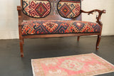 Distressed Oushak rug with faded blush pink and ivory geometric pattern.