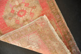 Distressed vintage Oushak rug showing blush pink pile, exposed foundation, selvages, and fringe.