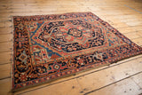 The classic turtle samovar border framing the bold medallion of a vintage Persian Heriz rug.