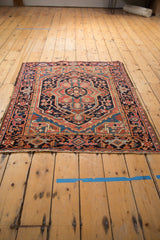 Angled view of a vintage Heriz rug's bold geometric medallion and classic turtle samovar border.