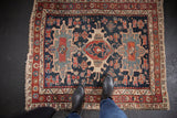 Antique Karaja rug corner, navy field, red geometric border, and tattered fringe.