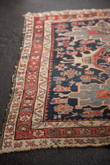 Antique Karaja rug: tattered edge, intricate floral borders, navy, wine red, and ivory.
