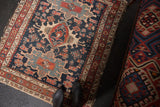 Antique Karaja rug corner, highlighting navy field, red floral border, and tattered fringe.