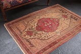 Curvilinear cherry red medallion, ivory floral field, on a vintage Farahan Sarouk rug.