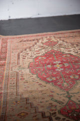 Low pile of a vintage Farahan Sarouk rug, featuring a cherry red medallion and ivory floral field.