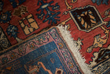 Folded vintage Bijar rug corner, red Harshang field, blue border, and hand-knotted fringe.