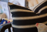 Textured herringbone weave on khaki stripes of a black throw pillow.
