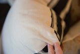 Close-up of the khaki fabric texture on the throw pillow, hand revealing subtle stripes.