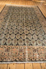 Distressed Oushak rug's geometric border and faded palmette patterns in pale apricot, black, and ivory.