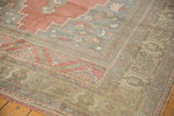 Corner of distressed Oushak rug with faded raspberry blush spandrel and muted floral borders.