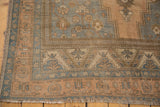 Vintage Distressed Oushak rug corner, pale apricot and slate blue floral borders, low pile, fringe.