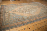 Hand-knotted Oushak rug corner, showcasing distressed texture and detailed blue and apricot borders.