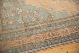 Distressed Oushak rug border with pale apricot and slate blue intricate floral motifs.