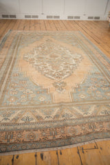 Intricate floral motifs and low distressed pile in pale apricot and slate blue on vintage Oushak rug.