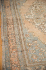 Distressed Oushak rug's border with pale apricot, slate blue, and bronze floral motifs.