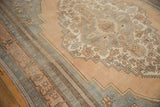 Distressed Oushak carpet border showing scalloped contour and muted floral motifs in apricot and blue.
