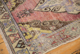 Close-up of vintage distressed Oushak runner, showing worn mauve field and patterned beige border.