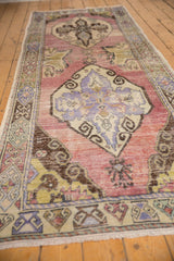 Distressed Oushak runner showing central leaf motif, geometric border, and soft mauve tones.
