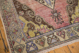 Worn texture and distinct border pattern of the Oushak rug in mauve, beige, and gold.