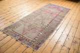 Distressed vintage Oushak runner, highlighting geometric stepped medallion and serrated leaf border in mauve and gold.