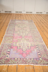 Distressed Oushak runner end, visible geometric border, mauve and gold tones, with pile wear.