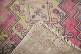 Distressed mauve, dusty gold, and blue serrated geometric pattern with visible hand-knotted foundation.
