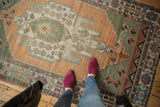Distressed Oushak rug with apricot field, sage medallion, aubergine floral palmettes, worn pile.