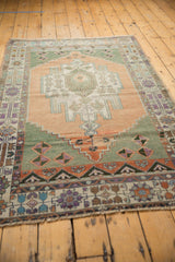 Distressed texture and colorful floral palmettes on the border of a vintage Oushak rug.
