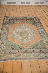 Vintage distressed Oushak rug corner with apricot field, sage green, and colorful floral borders.