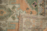 Folded vintage Oushak rug revealing distressed apricot pile, fringe, and tightly woven reverse.
